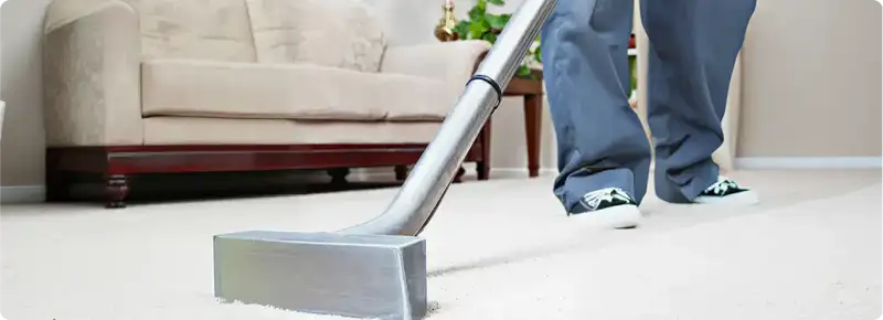 Carpet cleaning technician using a hot-water extraction wand on a light-colored carpet in a living room, Atlanta, GA.