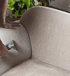 Professional upholstery cleaner deep-cleaning a fabric sofa with a handheld extraction tool and hose Atlanta, GA.